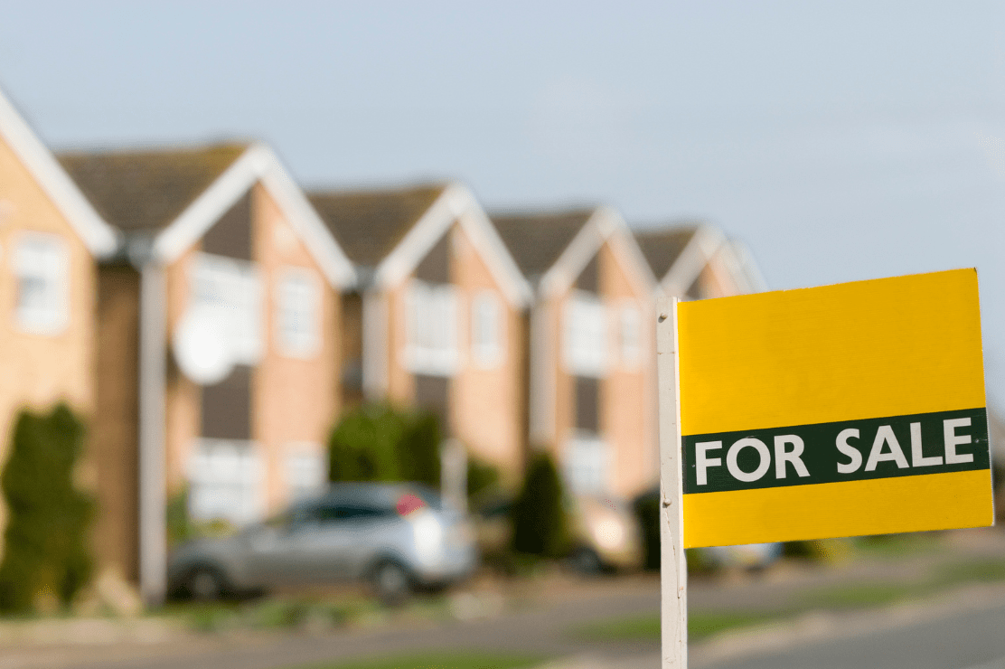 'For Sale' sign in front of a set of homes